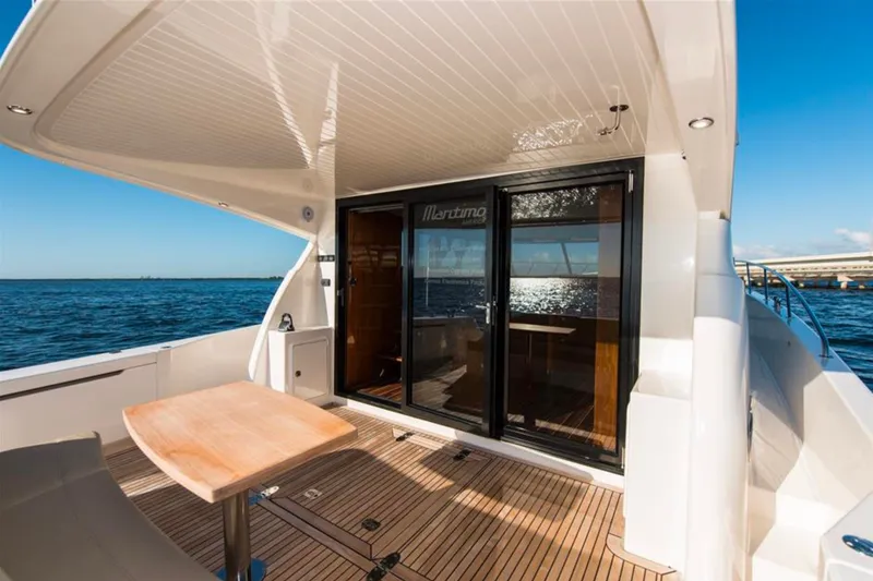 Slide: The Image of 2016 Maritimo M51 yacht deck with wooden table, overlooking serene ocean view. - 15