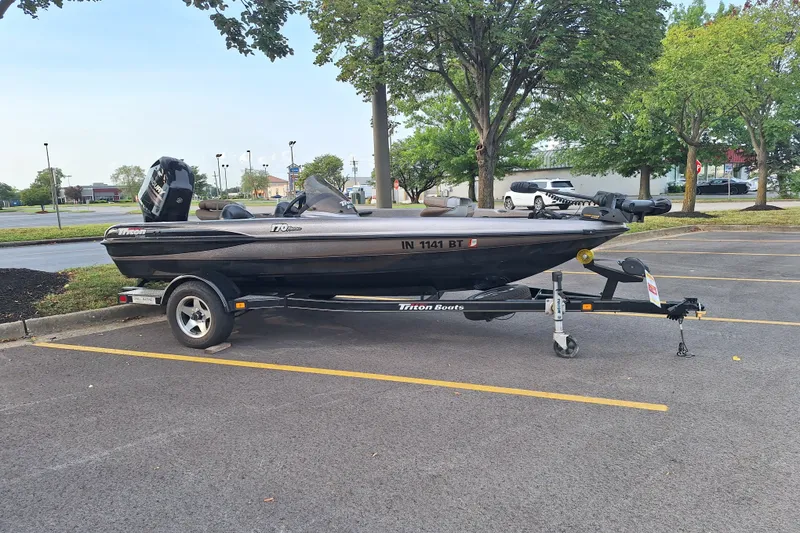 Slide: The Image of 2000 Triton Tr-17 boat on trailer in parking lot, surrounded by trees. - 8