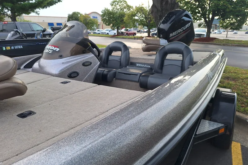 Slide: The Image of 2000 Triton Tr-17 boat with Mercury engine, parked outdoors near trees and vehicles. - 6