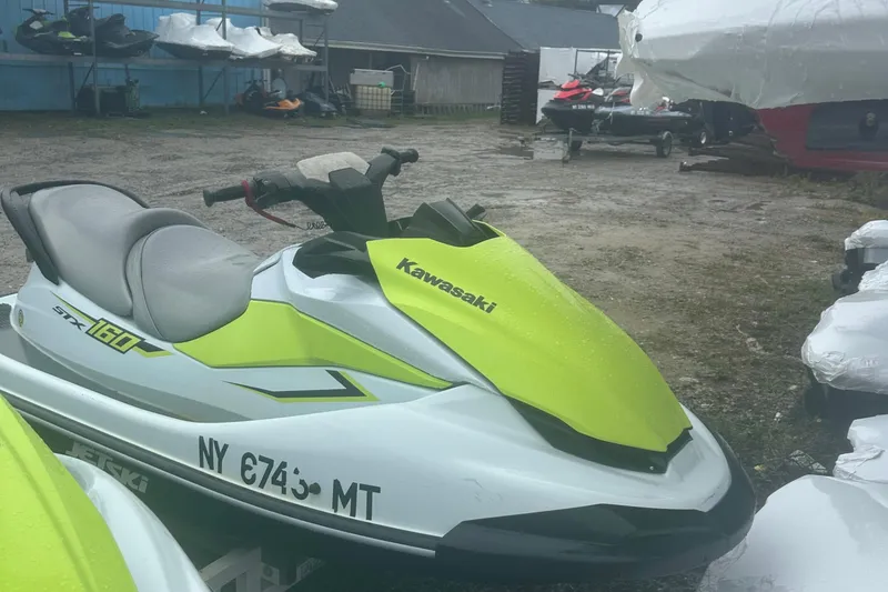 The Image of 2023 Kawasaki Jetski STX 160 in a storage yard, featuring a vibrant green and white design. - 0