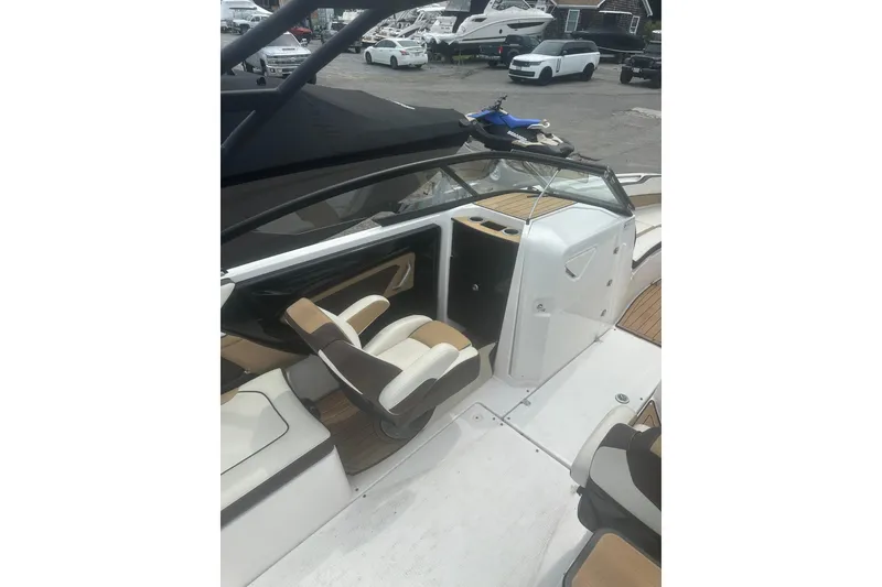 Slide: The Image of 2023 Yamaha Boats 252S interior with seating and dashboard, parked in a marina. - 33