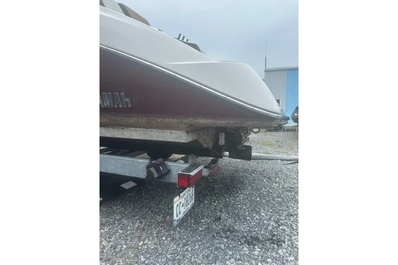 Slide: The Image of 2023 Yamaha Boats 252S on trailer, rear view, parked on gravel. - 18
