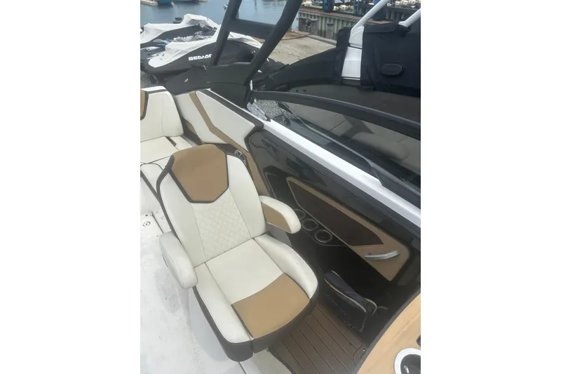 Slide: The Image of 2023 Yamaha Boats 252S interior with beige and white seating, docked by the water. - 31