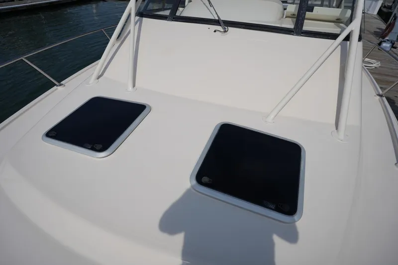 Slide: The Image of 2018 Grady-White Express 330 boat deck with two hatches, docked by the water. - 40