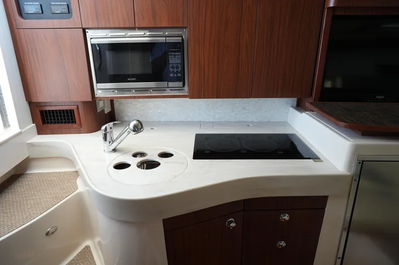 Slide: The Image of 2018 Grady-White Express 330 boat kitchen with microwave, stove, and wooden cabinetry. - 27