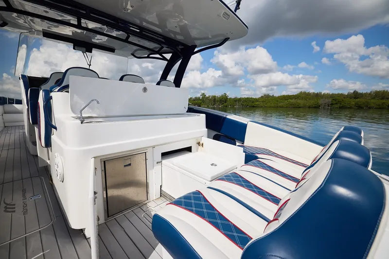 Slide: The Image of 2018 Midnight Express 43 Open boat interior with seating and storage, on a calm lake. - 13