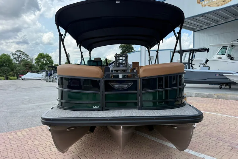 Slide: The Image of 2027 Bennington 22 M Quad Bench pontoon boat with canopy, parked outdoors. - 1
