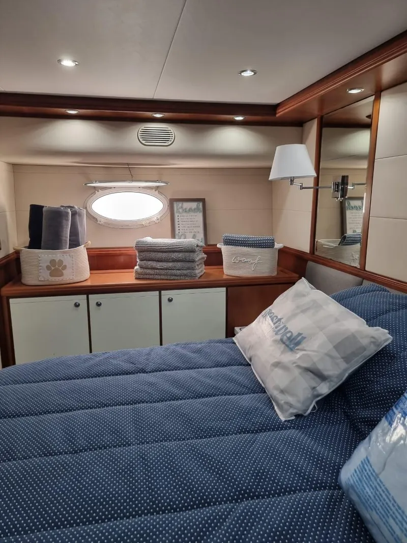 Slide: The Image of Cozy bedroom in a 2008 Bertram 670 Convertible yacht with blue bedding and storage cabinets. - 24