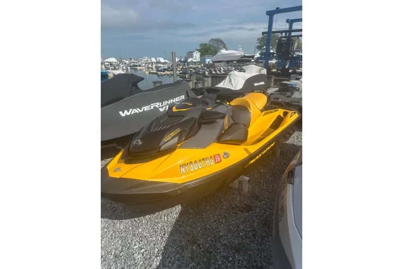 The Image of 2022 Sea-Doo GTR 230 jet ski in vibrant yellow, parked at a marina. - 1