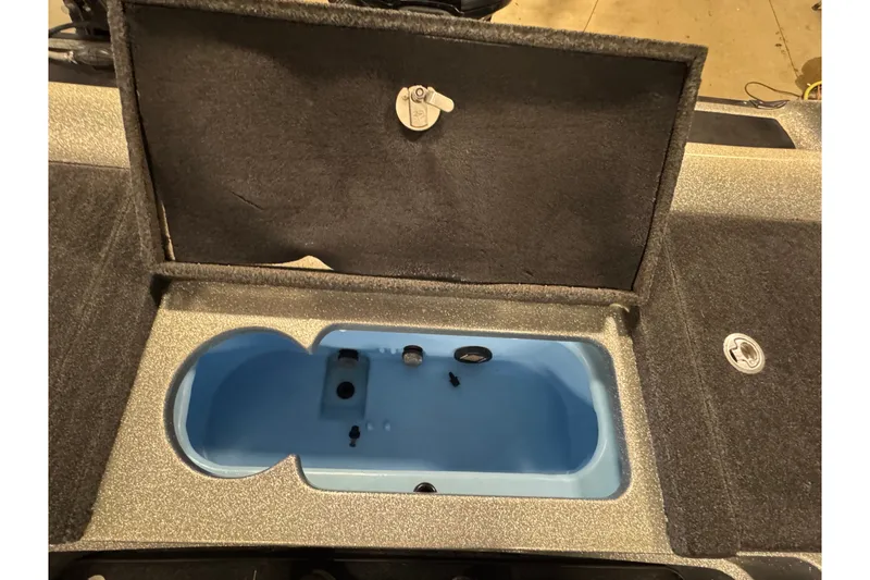 Slide: The Image of Open storage compartment in a 2015 Nitro ZV21 boat, featuring a blue interior. - 13