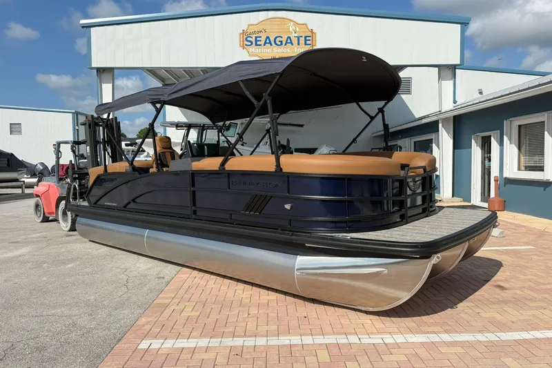 The Image of 2027 Bennington 24 M Quad Bench pontoon boat at dealership, featuring sleek design and canopy. - 0