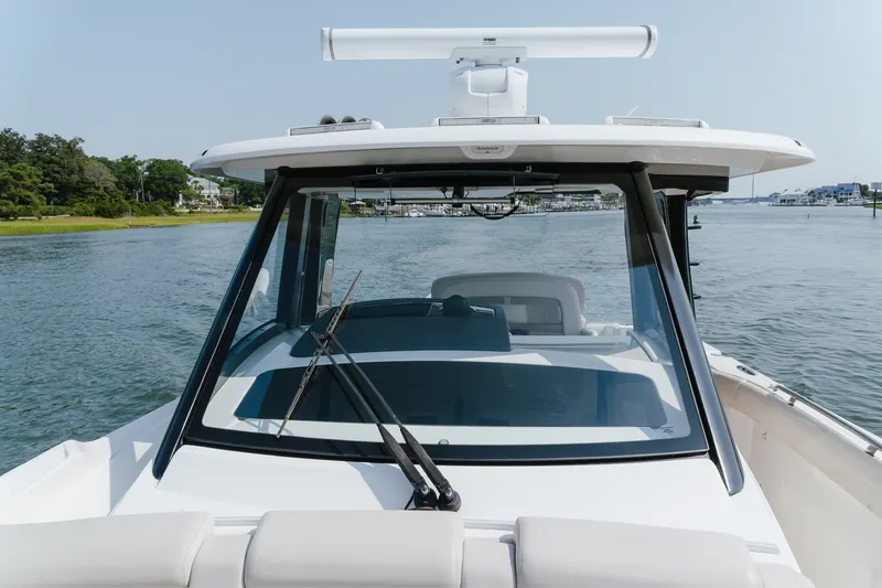 Slide: The Image of 2023 Boston Whaler 350 Realm boat on calm water, showcasing sleek design and windshield. - 22