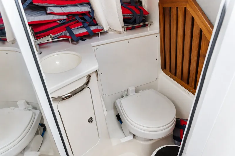Slide: The Image of 2023 Boston Whaler 350 Realm boat bathroom with sink, toilet, and life jackets. - 15
