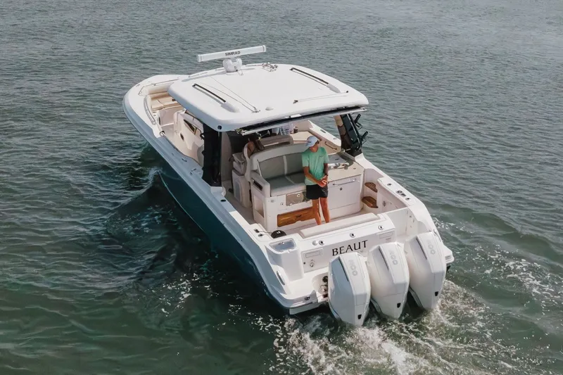 Slide: The Image of 2023 Boston Whaler 350 Realm cruising on water, featuring triple outboard engines. - 7