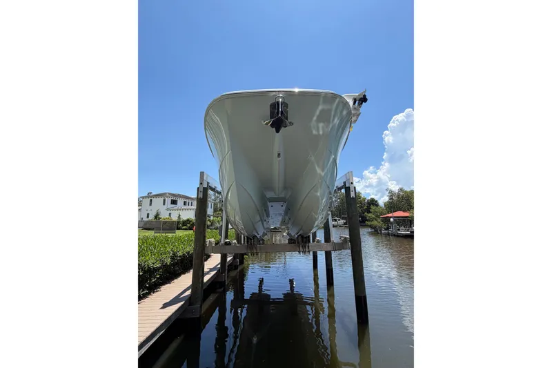 Slide: The Image of 2024 Invincible 33 Catamaran on lift, viewed from below, against clear blue sky. - 1