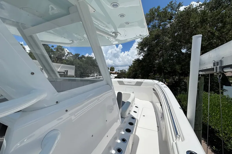Slide: The Image of 2024 Invincible 33 Catamaran boat deck with seating and rod holders, under a clear blue sky. - 30