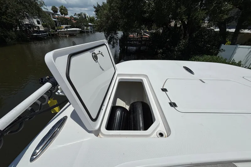 Slide: The Image of Open storage compartment on 2024 Invincible 33 Catamaran, docked near lush greenery. - 12