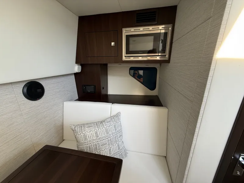 Slide: The Image of Interior of a modern yacht with a white sofa, wooden table, and microwave. - 24