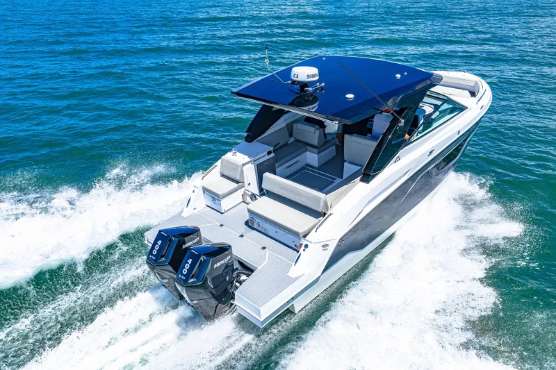 Slide: The Image of The 2027 Cruisers Yachts 34 GLS OB speeds across blue water. It features twin outboard engines and a sleek design. - 17