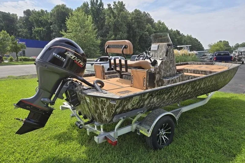 Slide: The Image of Avid 20 Rogue CC 2027 boat with camouflage design on a trailer, parked on grass. - 9