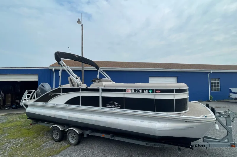 The Image of 2019 Bennington SX 23 Swingback pontoon boat on trailer, parked near blue building. - 1