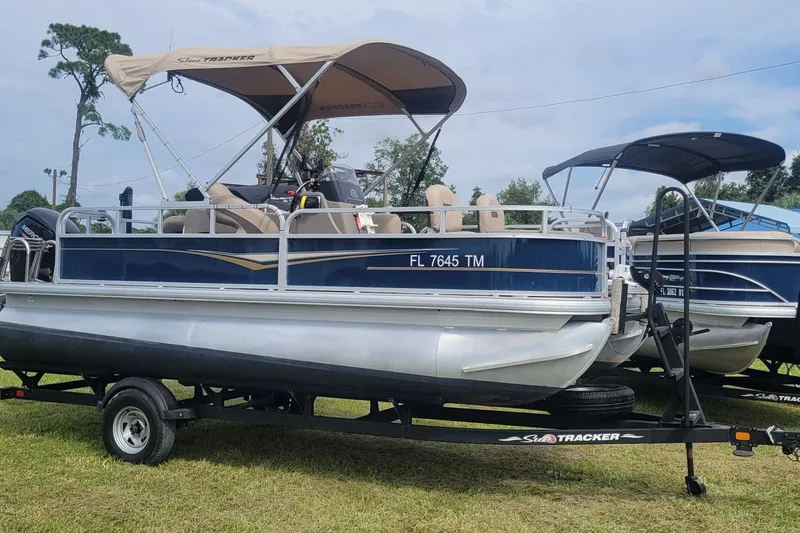 The Image of 2023 Sun Tracker Bass Buggy 18 DLX pontoon boat on trailer, parked on grass. - 8