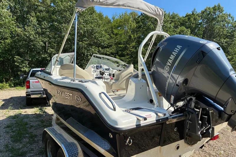 Slide: The Image of 2023 Key West 203 DFS boat with Yamaha engine, parked on a trailer in a wooded area. - 17
