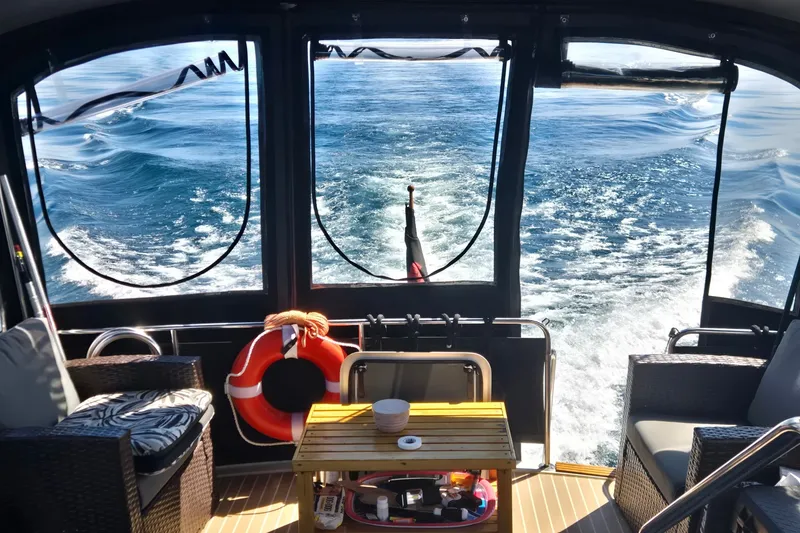 Slide: The Image of Aft view from 1988 Mainship 36 Double Cabin, featuring ocean waves and cozy seating. - 6