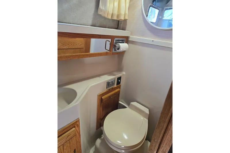 Slide: The Image of 1988 Mainship 36 Double Cabin bathroom with toilet, sink, and wooden cabinetry. - 11