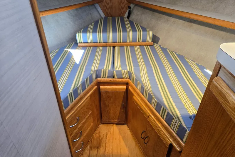 Slide: The Image of 1988 Mainship 36 Double Cabin interior with striped bedding and wooden cabinetry. - 9