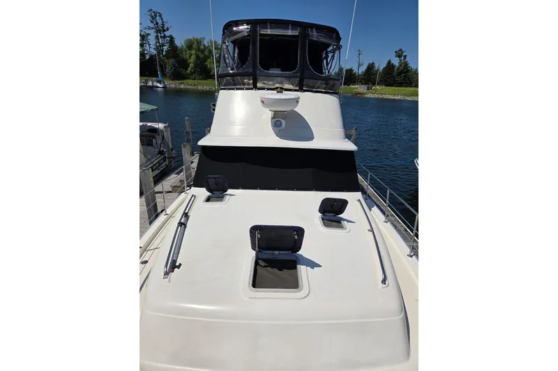 Slide: The Image of 1988 Mainship 36 Double Cabin yacht docked by a serene waterfront. - 3