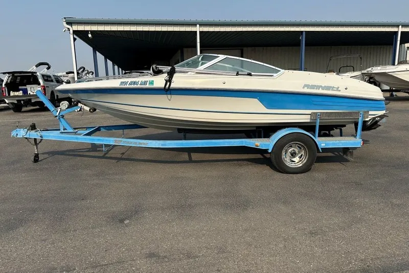 Slide: The Image of 1994 Reinell 184 boat on a blue trailer, parked outdoors. - 1