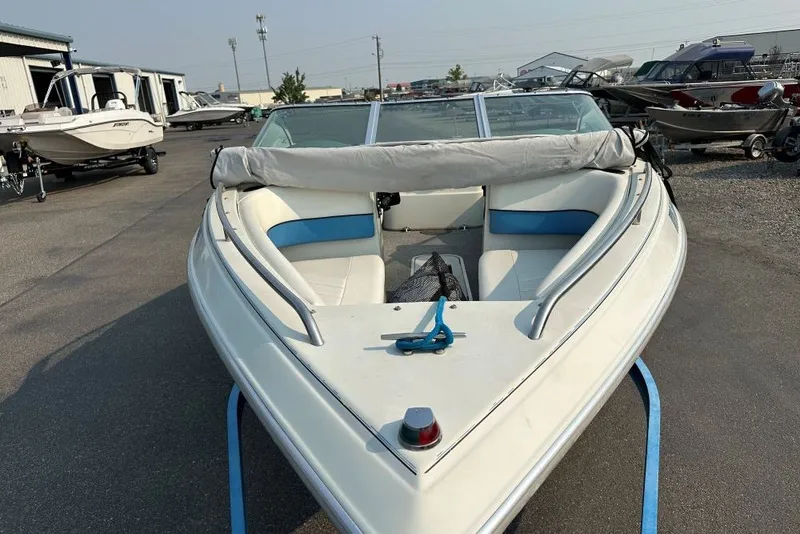 Slide: The Image of 1994 Reinell 184 boat with white and blue interior, parked in a marina. - 2