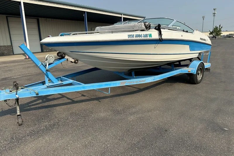 The Image of 1994 Reinell 184 boat on blue trailer, parked outdoors. - 0
