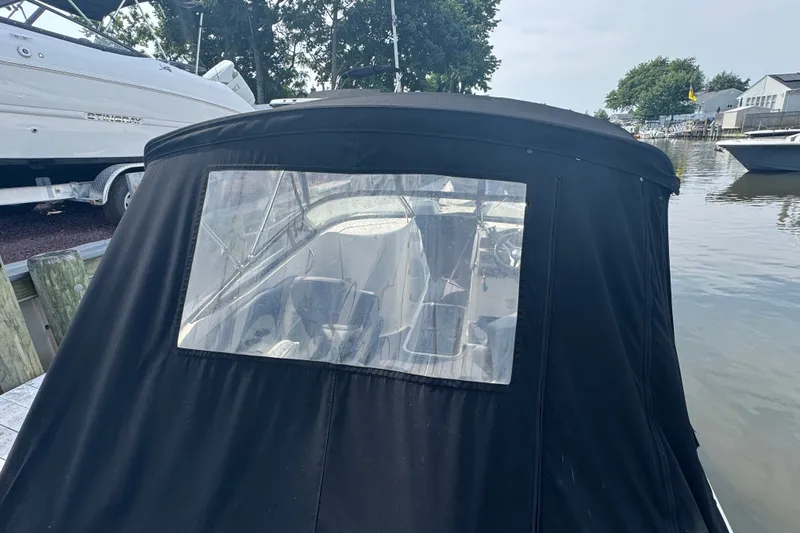 Slide: The Image of 2022 Stingray 214 LR boat with black cover docked by the water. - 4