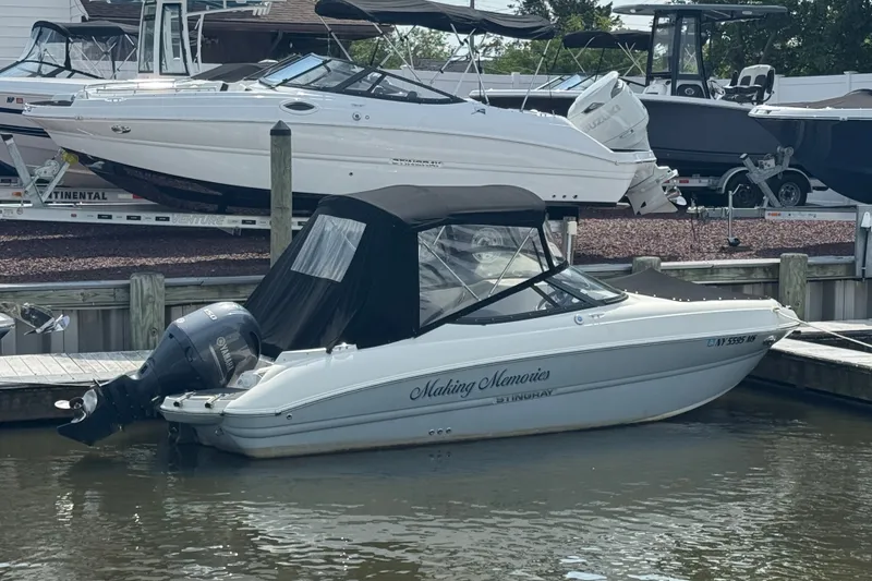 The Image of 2022 Stingray 214 LR boat docked, featuring a Yamaha outboard motor and black canopy. - 1
