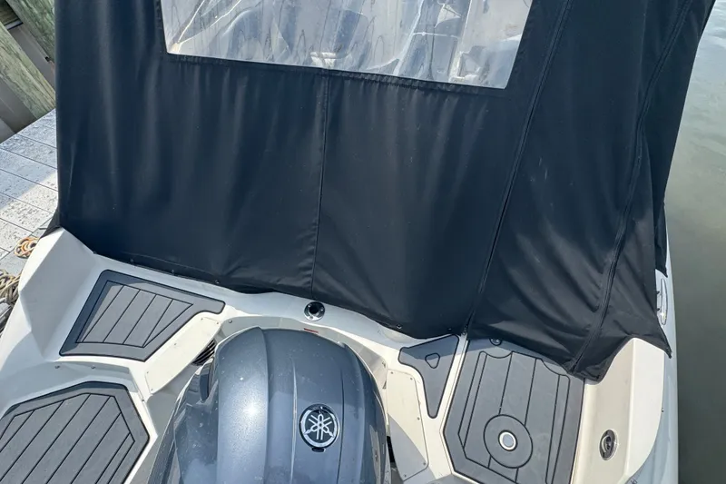 Slide: The Image of 2022 Stingray 214 LR boat with black cover and Yamaha engine, docked by the water. - 3