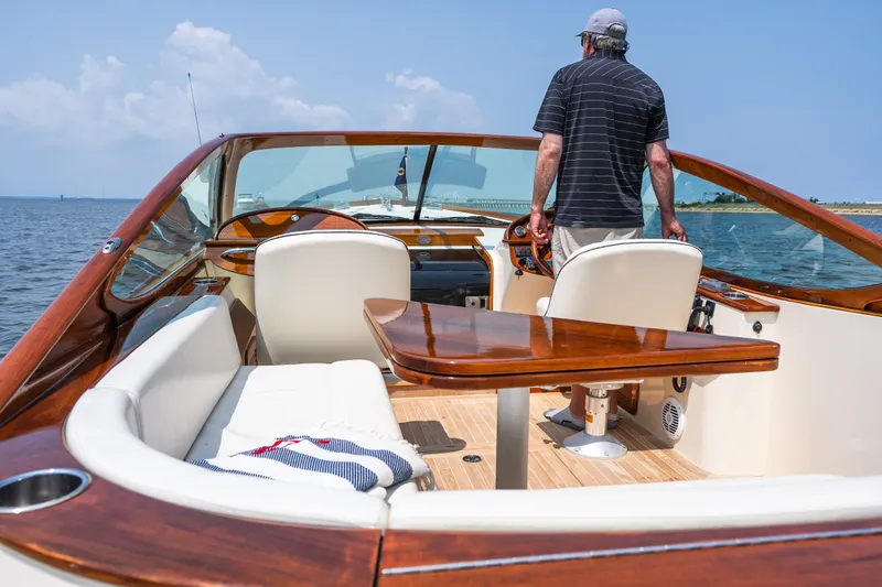 Slide: The Image of Man steering 2008 Hinckley Talaria 29R boat on open water, featuring elegant wooden interior. - 18