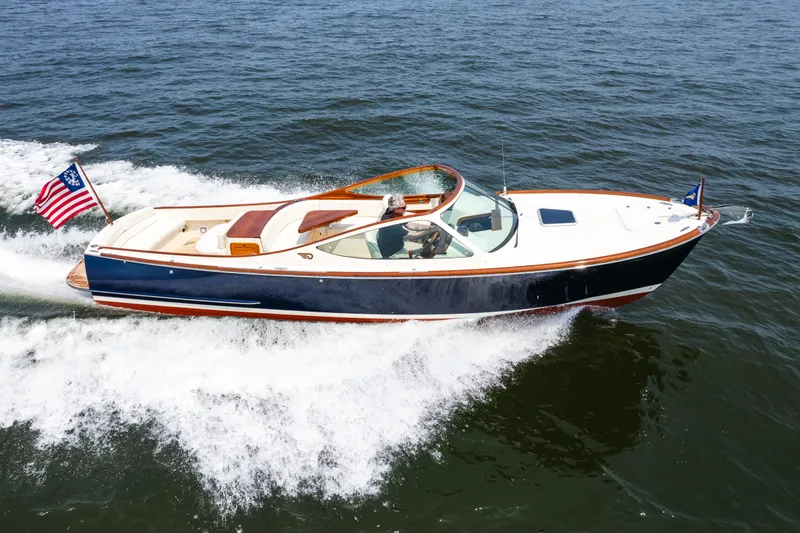 Slide: The Image of 2008 Hinckley Talaria 29R cruising on open water, displaying sleek design and American flag. - 12