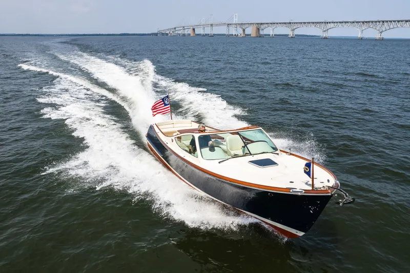 Slide: The Image of 2008 Hinckley Talaria 29R cruising on open water near a large bridge. - 11
