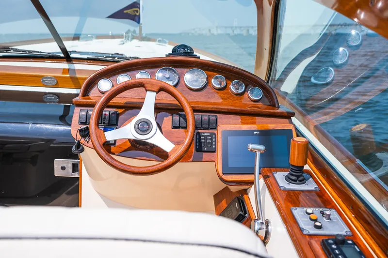 Slide: The Image of 2008 Hinckley Talaria 29R helm with wooden dashboard and modern controls on open water. - 21