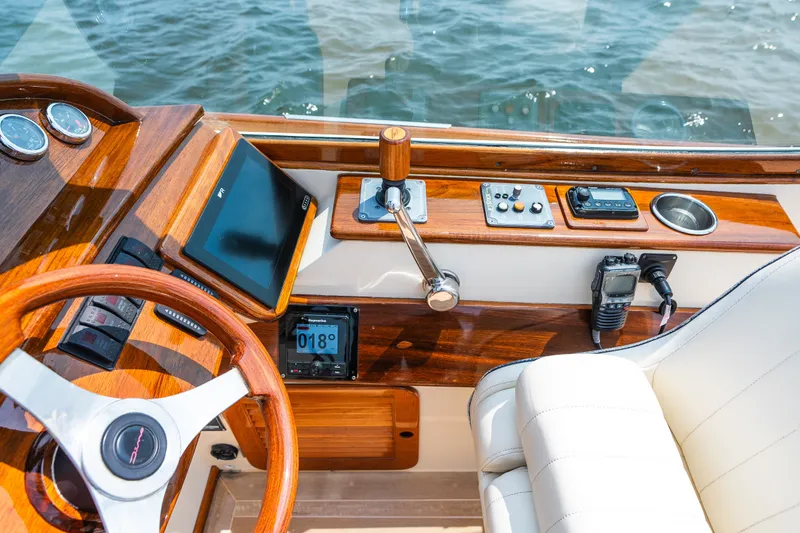 Slide: The Image of 2008 Hinckley Talaria 29R helm with wooden dashboard, steering wheel, and navigation instruments. - 22