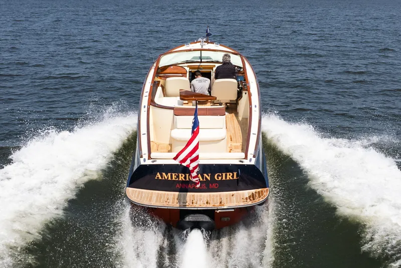 Slide: The Image of 2008 Hinckley Talaria 29R boat cruising on water, rear view with American flag. - 45