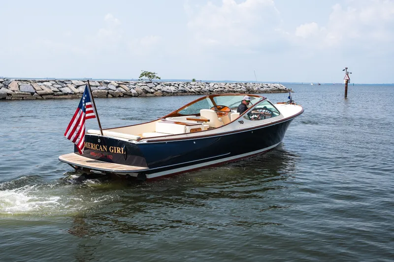 Slide: The Image of 2008 Hinckley Talaria 29R boat cruising near rocky shoreline, displaying American flag. - 13