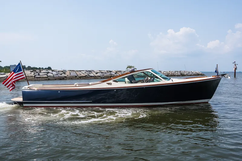 Slide: The Image of 2008 Hinckley Talaria 29R cruising on water with American flag, clear sky background. - 1