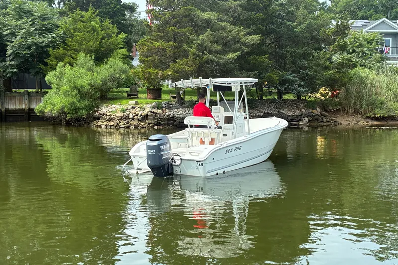 Slide: The Image of 2004 Sea Pro 206 Center Console boat on calm water near a lush shoreline. - 6