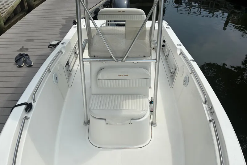 Slide: The Image of 2004 Sea Pro 206 Center Console boat docked, featuring white seating and stainless steel rails. - 10