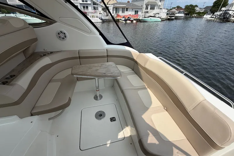 Slide: The Image of 2016 Formula 37 Performance Cruiser interior with beige seating and wooden table by the water. - 7