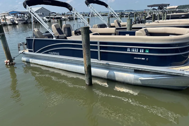 The Image of 2025 Harris Cruiser 230 pontoon boat docked at a marina on a sunny day. - 1