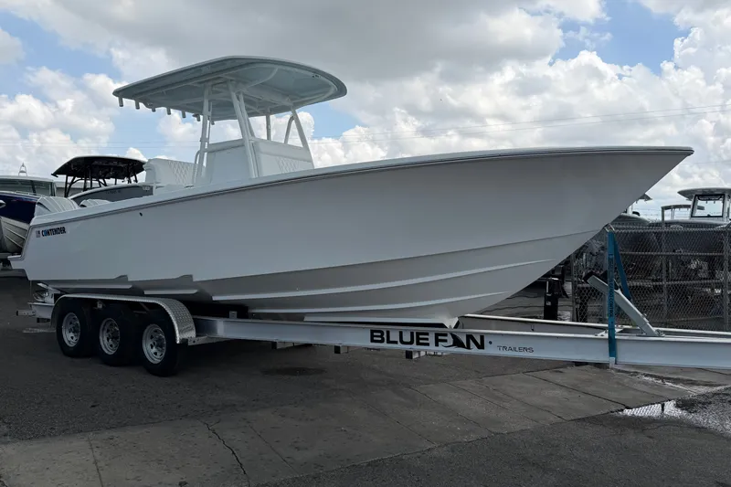 The Image of 2027 Contender 30 ST boat on Blue Fin trailer, parked outdoors under cloudy sky. - 0